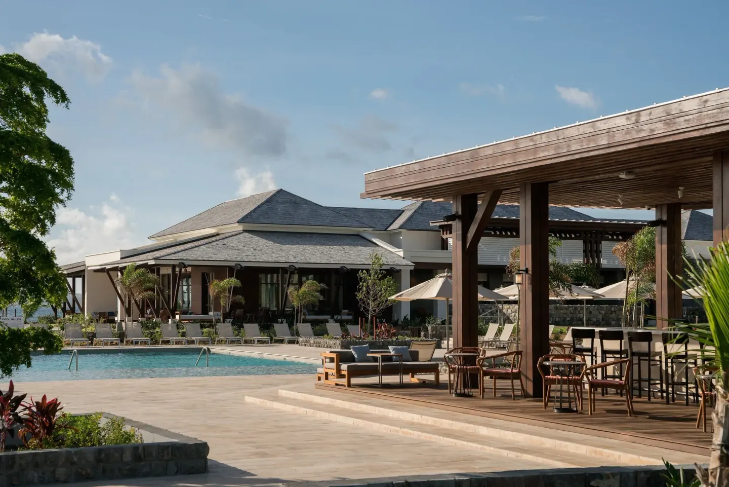 Poolside terrace with shaded seating and resort buildings at Park Hyatt St. Kitts.
