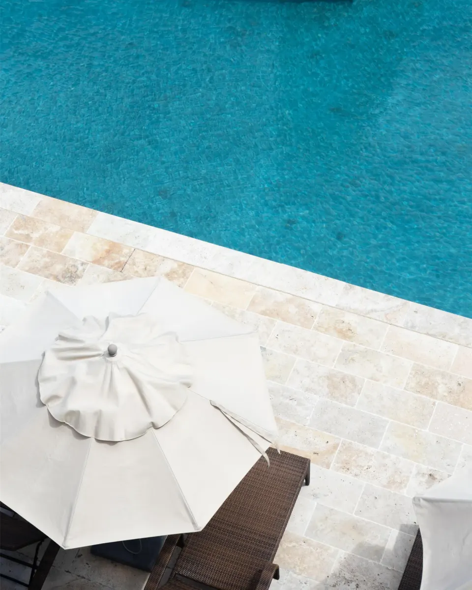 Poolside umbrella and lounge chair beside blue water at Park Hyatt St. Kitts.