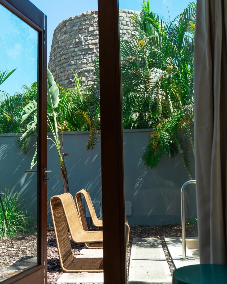 Open doors frame lounge chairs and palms in a private courtyard at Park Hyatt St. Kitts.