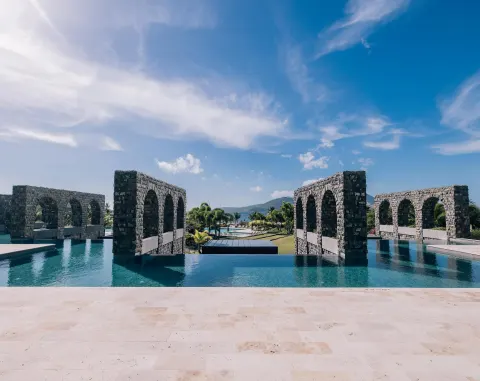 Reflecting pool with stone arch walls and ocean beyond at Park Hyatt St. Kitts.