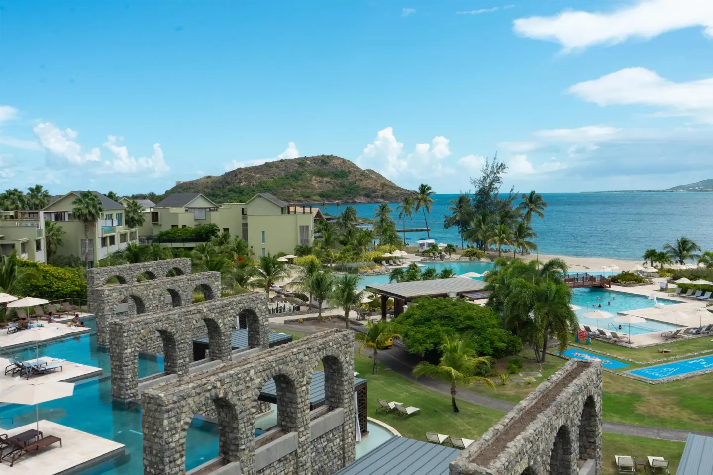 Resort pools, stone arches, palms, and ocean at Park Hyatt St. Kitts.
