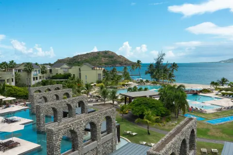 Resort pools, stone arches, palms, and ocean at Park Hyatt St. Kitts.