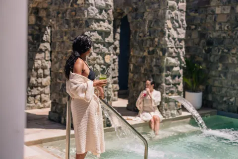 Guests beside a spa plunge pool with stone walls at Park Hyatt St. Kitts.