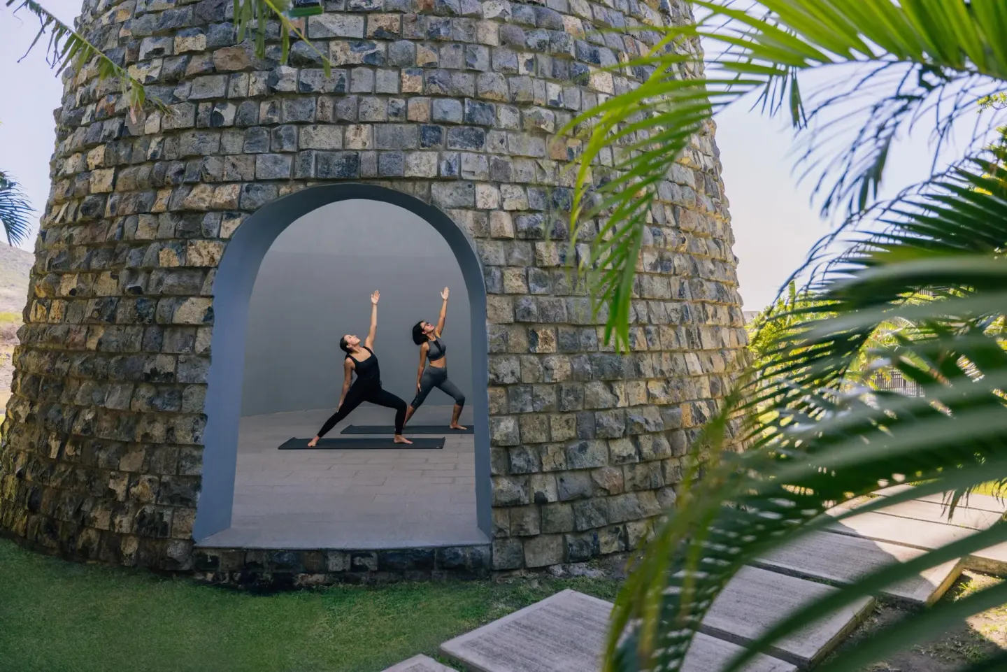 Two people practice yoga inside a stone tower at Park Hyatt St. Kitts.