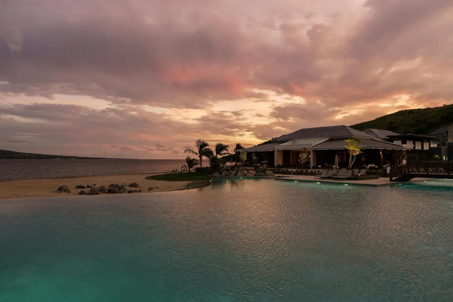 Pool and beachfront under a colorful sunset sky at Park Hyatt St. Kitts.