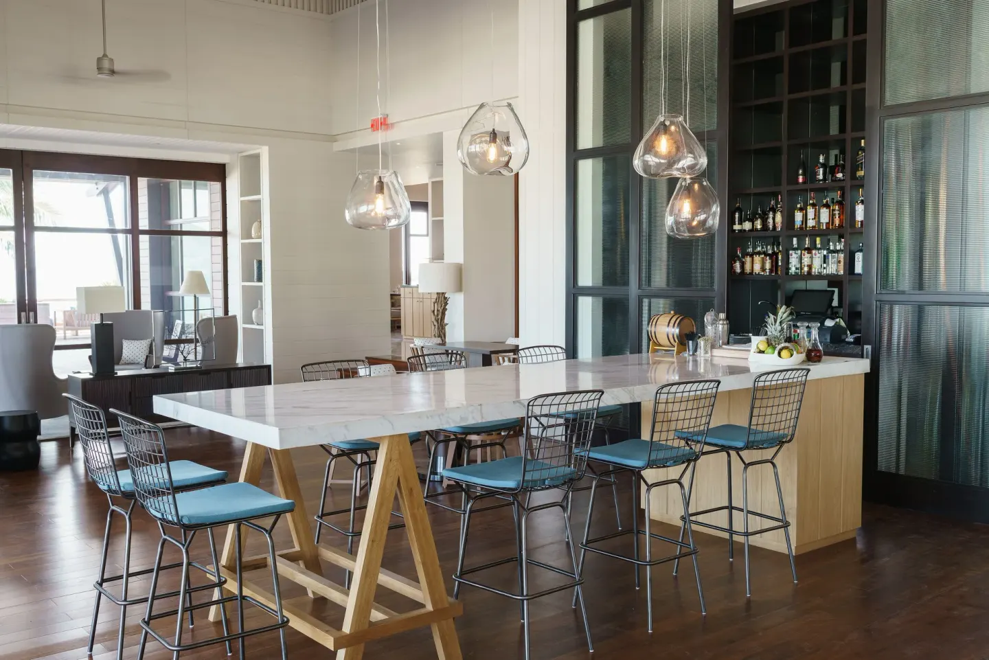 Bright bar counter with high stools and bottle shelves at Park Hyatt St. Kitts.