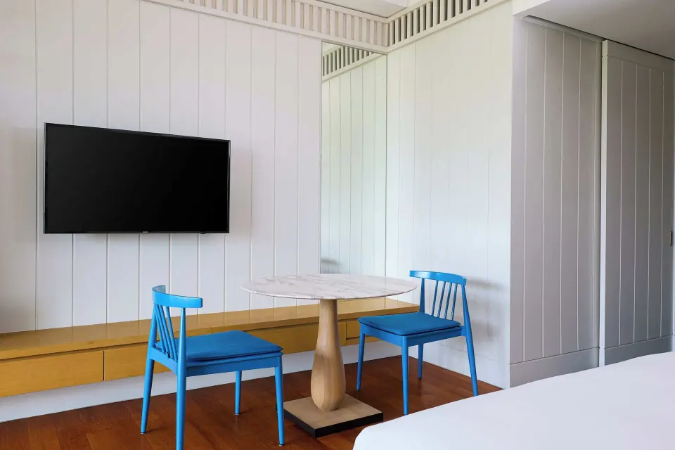 Guest room table, blue chairs, and wall-mounted TV at Park Hyatt St. Kitts.