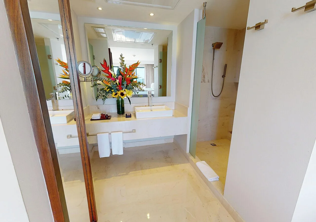 Guest bathroom with double sinks and glass shower at Park Royal Beach Cancun.