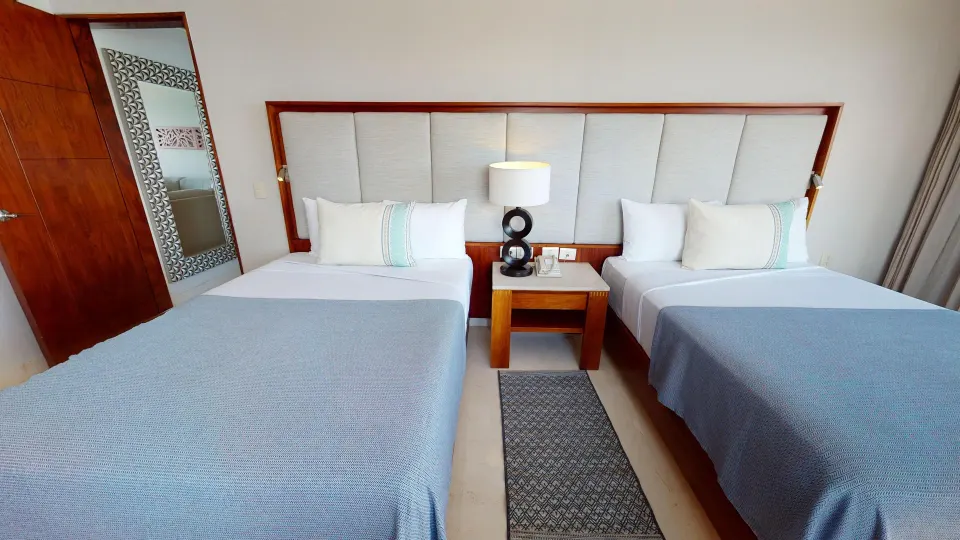 Two-bed guest room with padded headboard at Park Royal Beach Cancun.