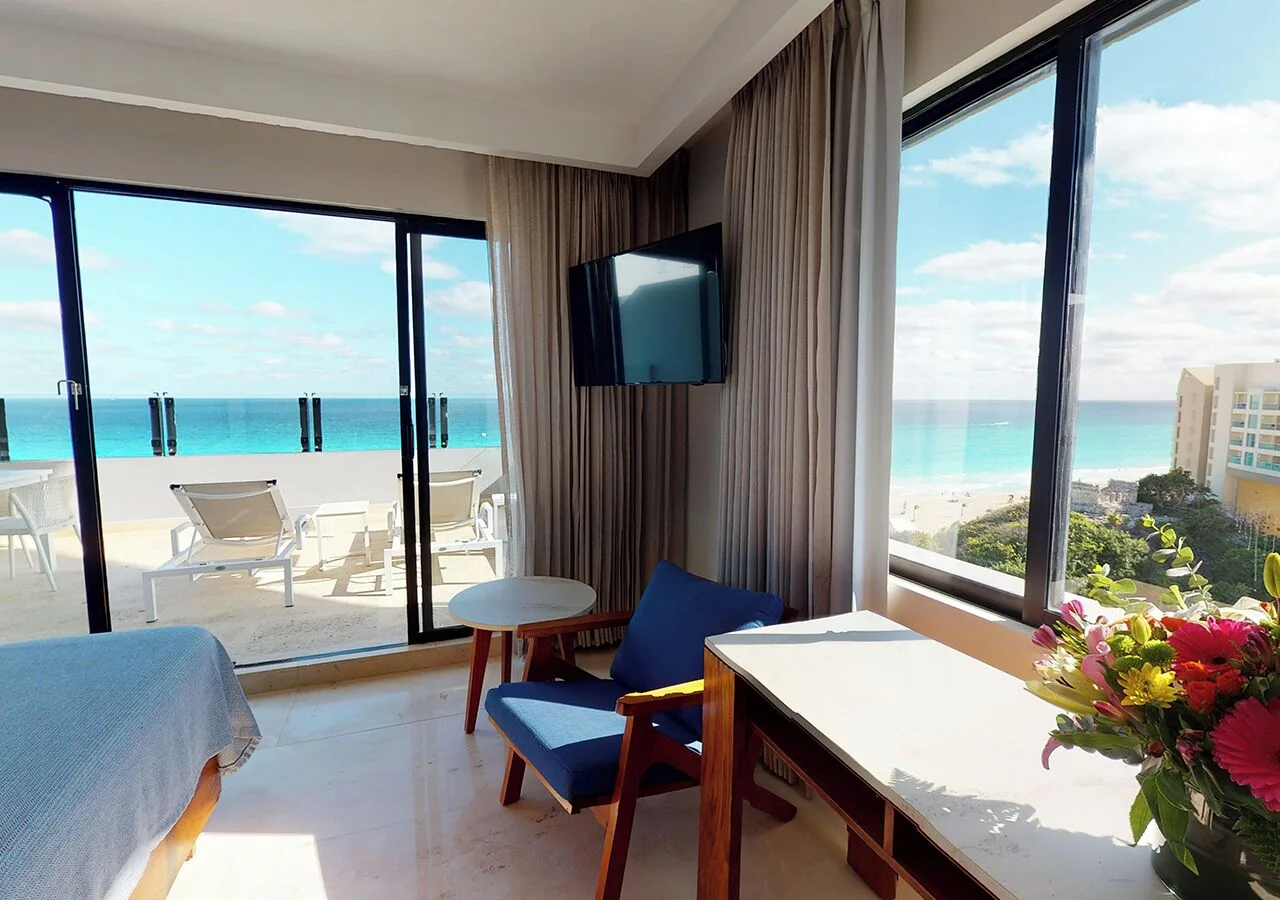 Guest room seating beside balcony and ocean view at Park Royal Beach Cancun.