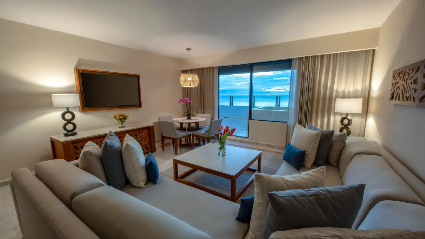 Suite living room with sofas and ocean-view balcony at Park Royal Beach Cancun.