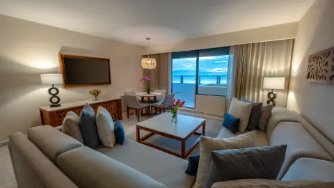 Suite living room with sofas and ocean-view balcony at Park Royal Beach Cancun.