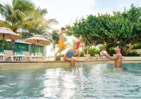 Guests playing in the pool near palms and loungers at Park Royal Beach Cancun.