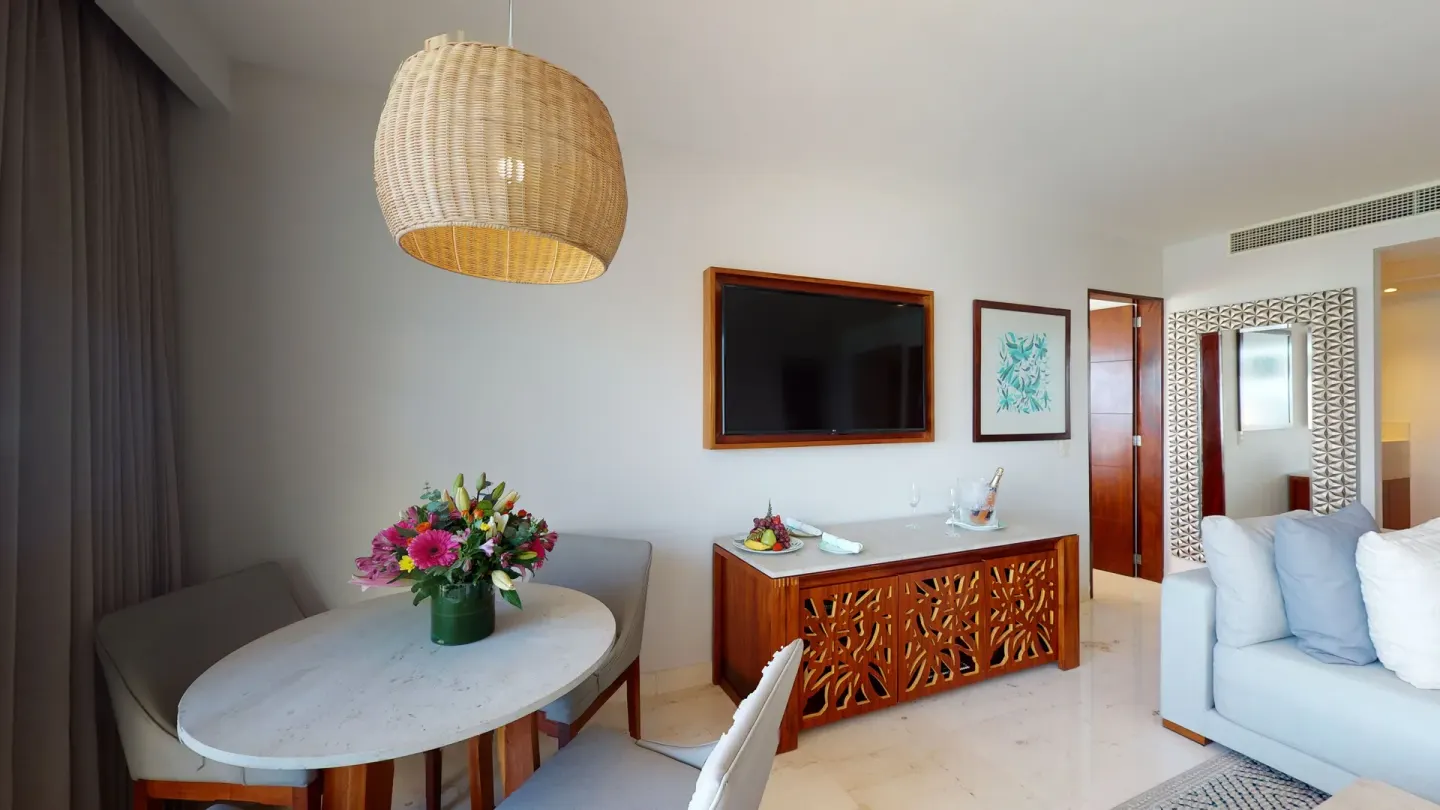 Dining table, TV console, and sofa in a suite at Park Royal Beach Cancun.