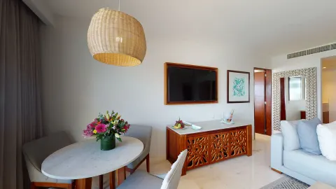 Dining table, TV console, and sofa in a suite at Park Royal Beach Cancun.