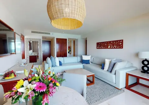 Suite living room with flowers, sectional sofa, and pendant light at Park Royal Beach Cancun.