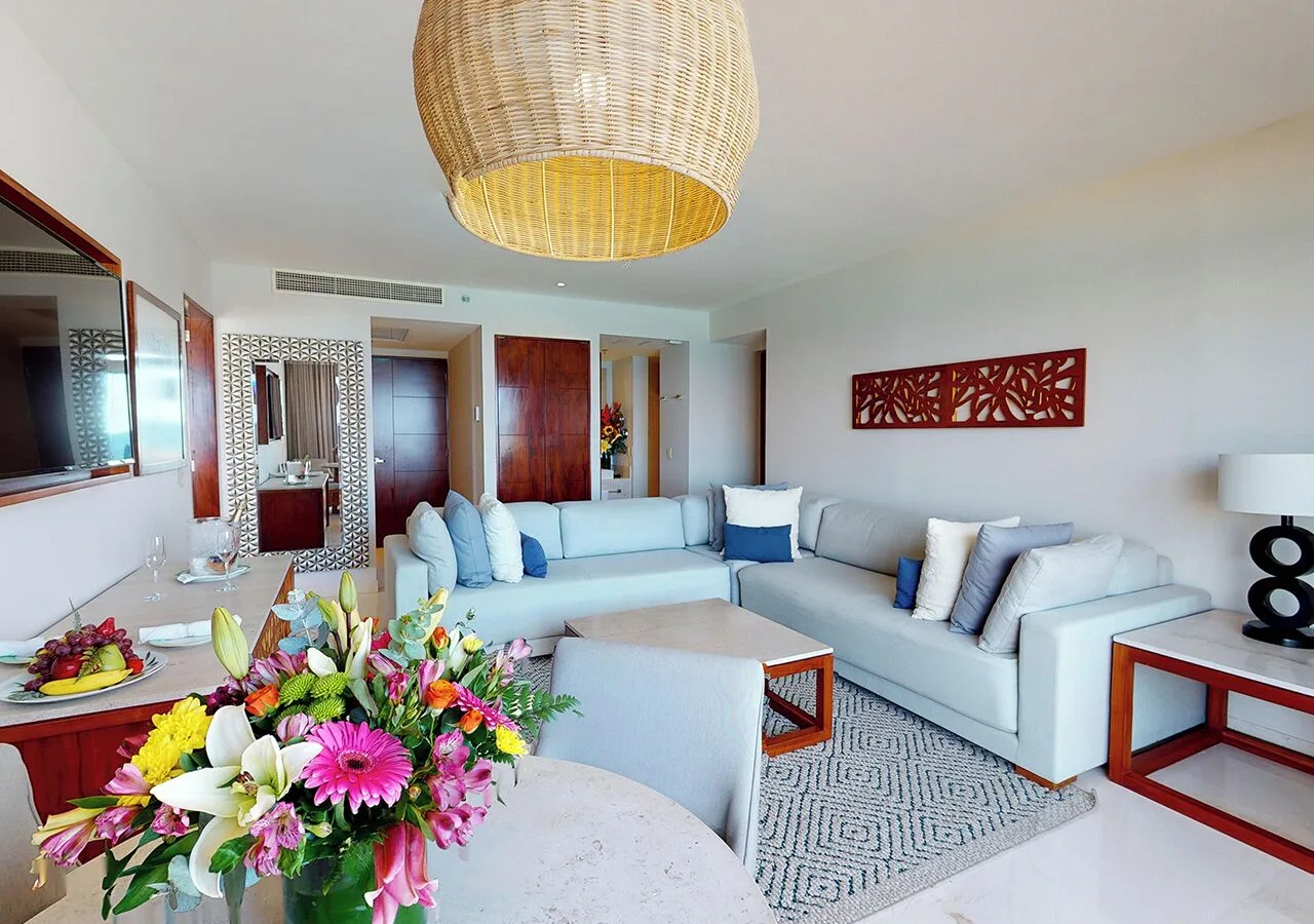 Suite living room with flowers, sectional sofa, and pendant light at Park Royal Beach Cancun.