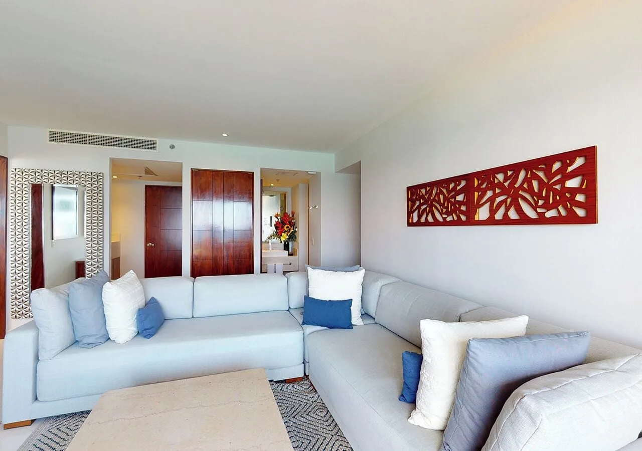 Sectional seating and hallway doors in a suite living room at Park Royal Beach Cancun.