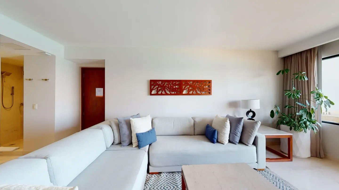 Sectional sofa beside a window and potted plant in a suite at Park Royal Beach Cancun.