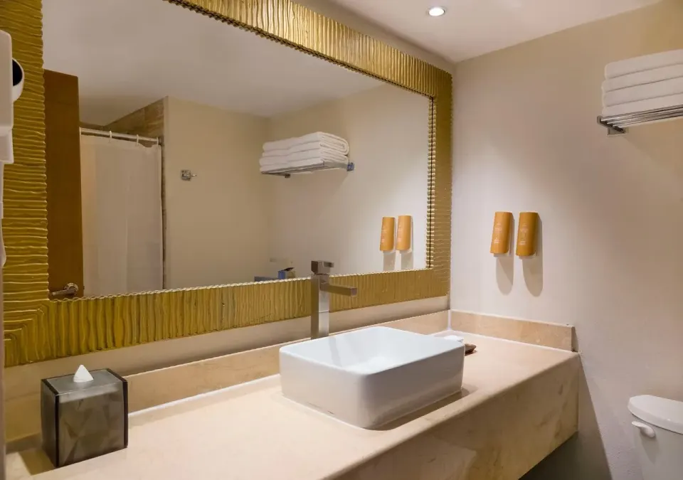 Deluxe room bathroom sink, mirror, towels, and shower curtain at Park Royal Beach Cancun.