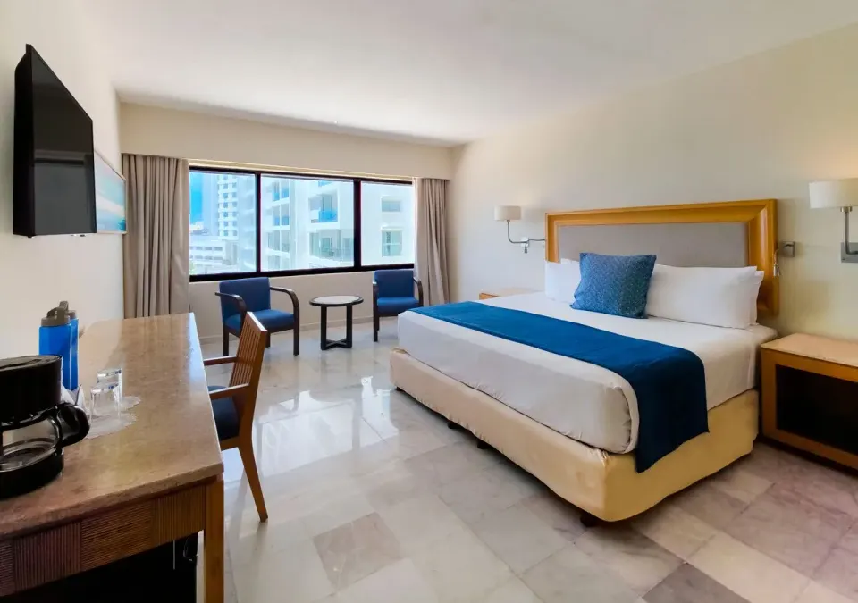 Deluxe king room with coffee maker, desk and blue seating at Park Royal Beach Cancun.