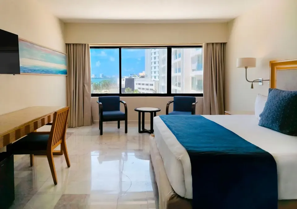 Deluxe king room with desk, seating and wide window at Park Royal Beach Cancun.