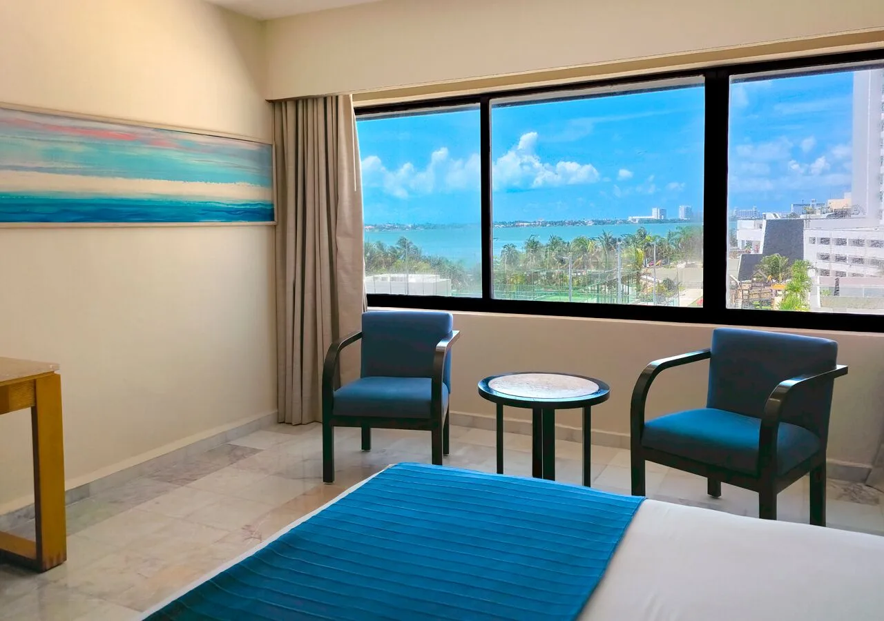 Deluxe room seating area with large lagoon-facing window at Park Royal Beach Cancun.
