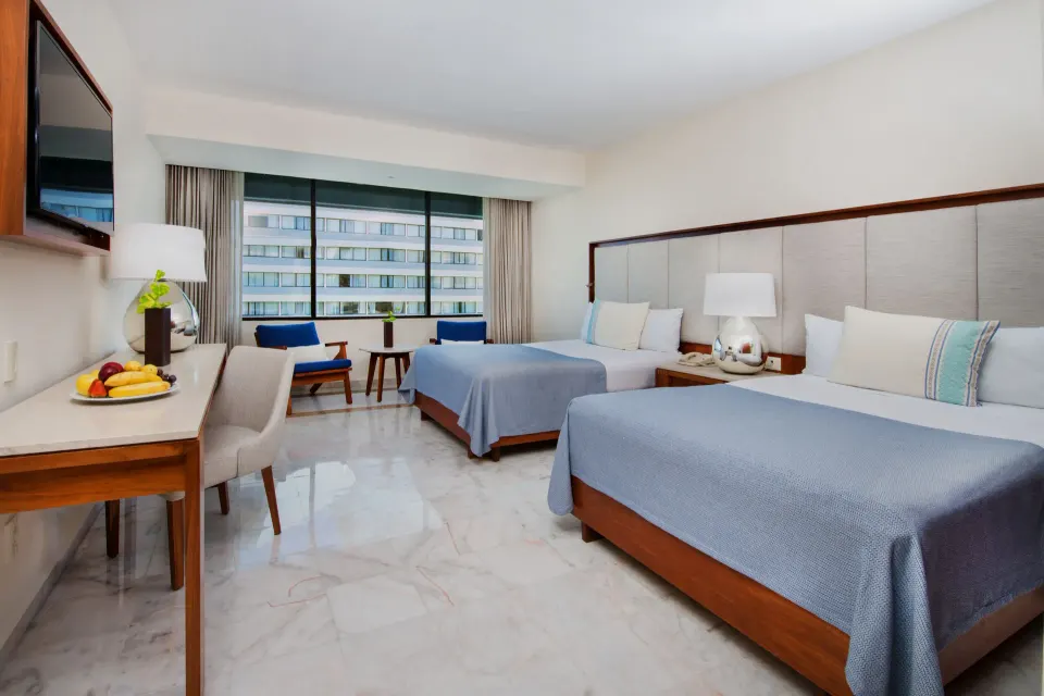 Deluxe room with two beds, desk, seating area and large window at Park Royal Beach Cancun.