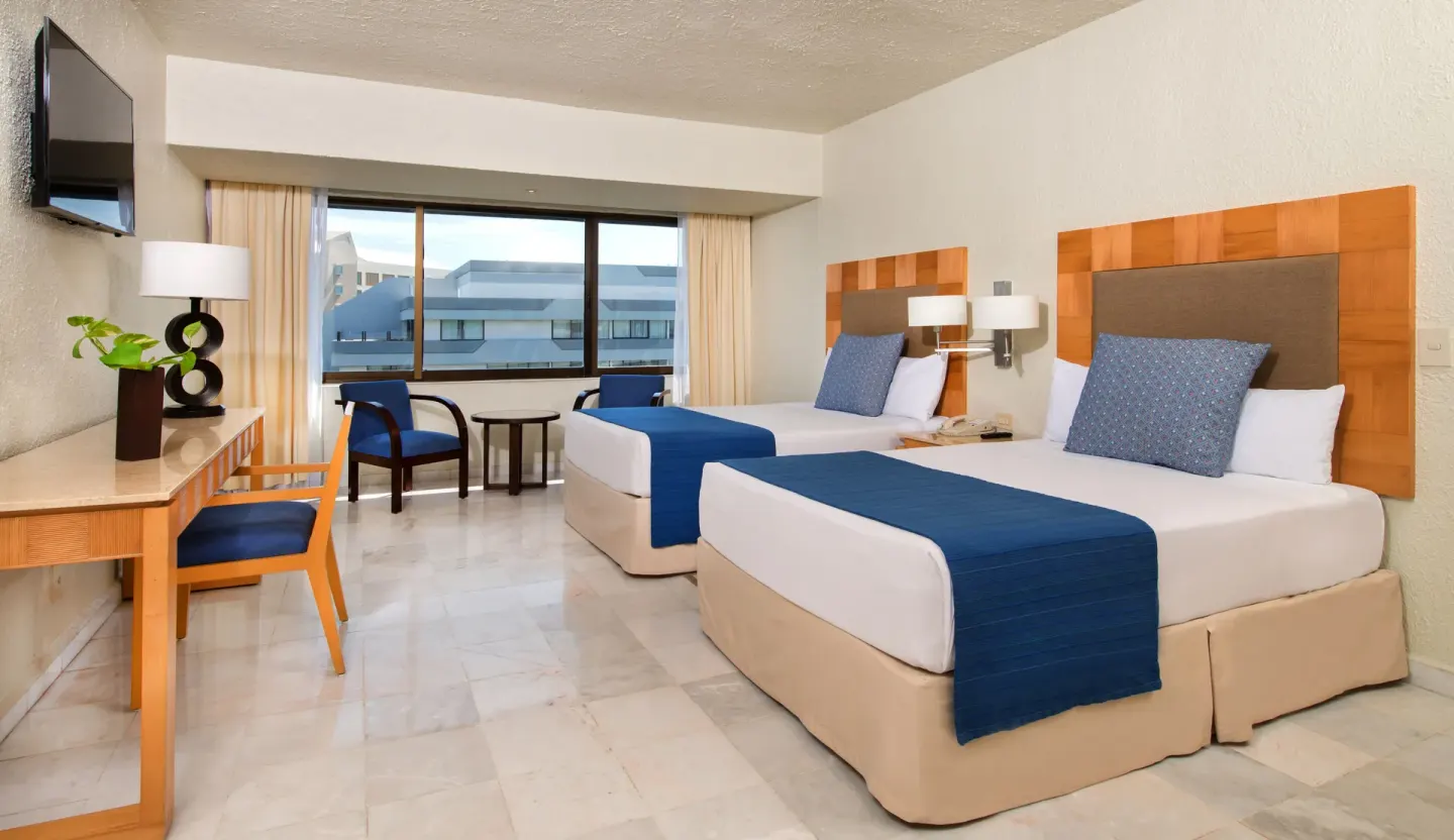 Deluxe room with two double beds, blue accents and a desk at Park Royal Beach Cancun.