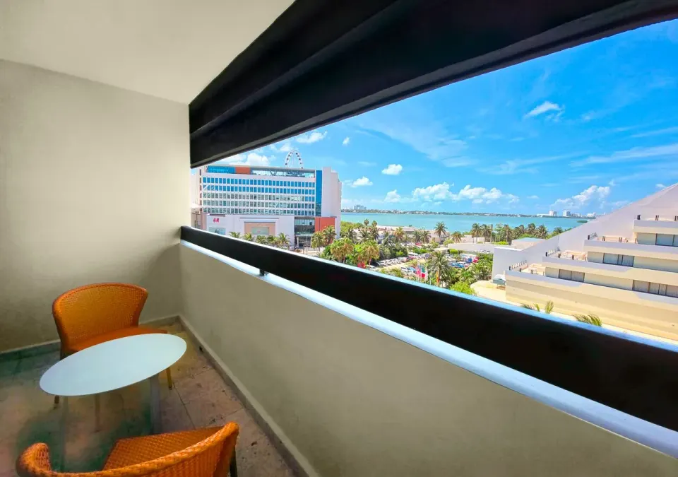 Family Suite balcony at Park Royal Beach Cancun with orange chairs, small table, and lagoon view.