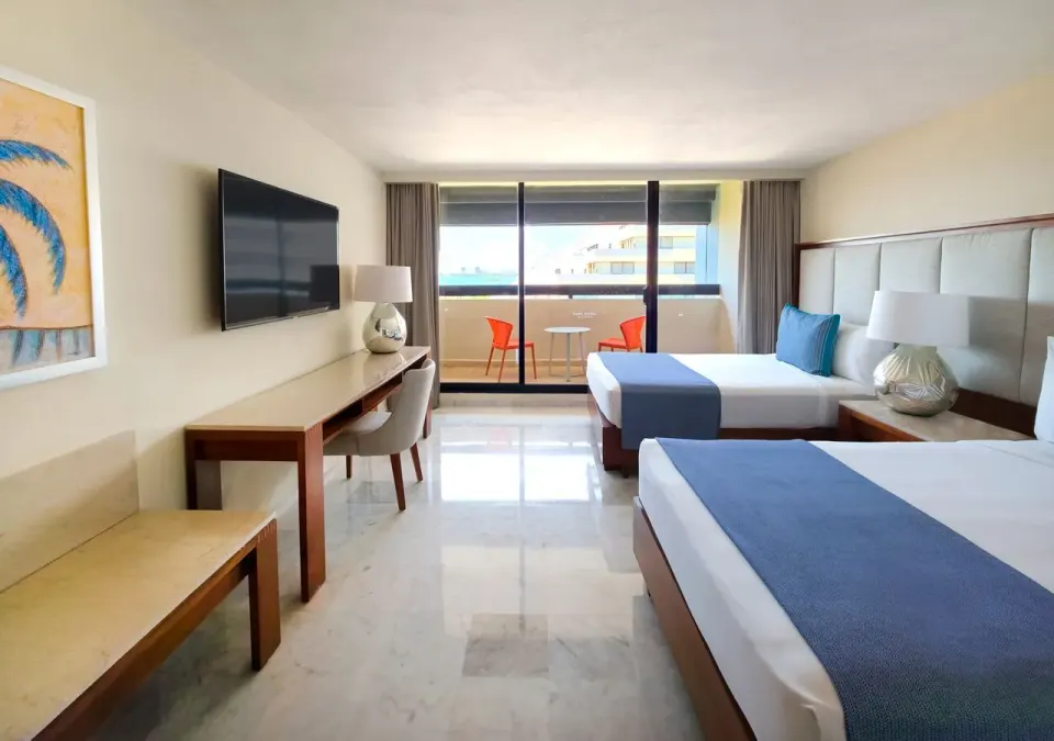 Family Suite bedroom at Park Royal Beach Cancun with two beds, desk, TV, and balcony doors.