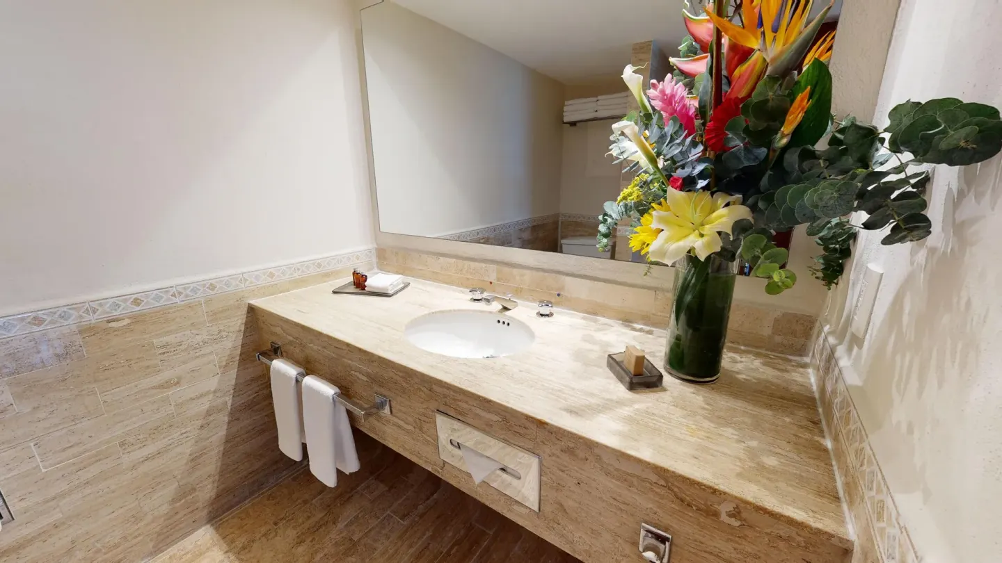 Family Suite bathroom vanity with sink, mirror, towels, and flowers at Park Royal Beach Cancun.