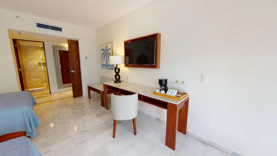 Family Suite desk, wall TV, coffee setup, and open bathroom doorway at Park Royal Beach Cancun.