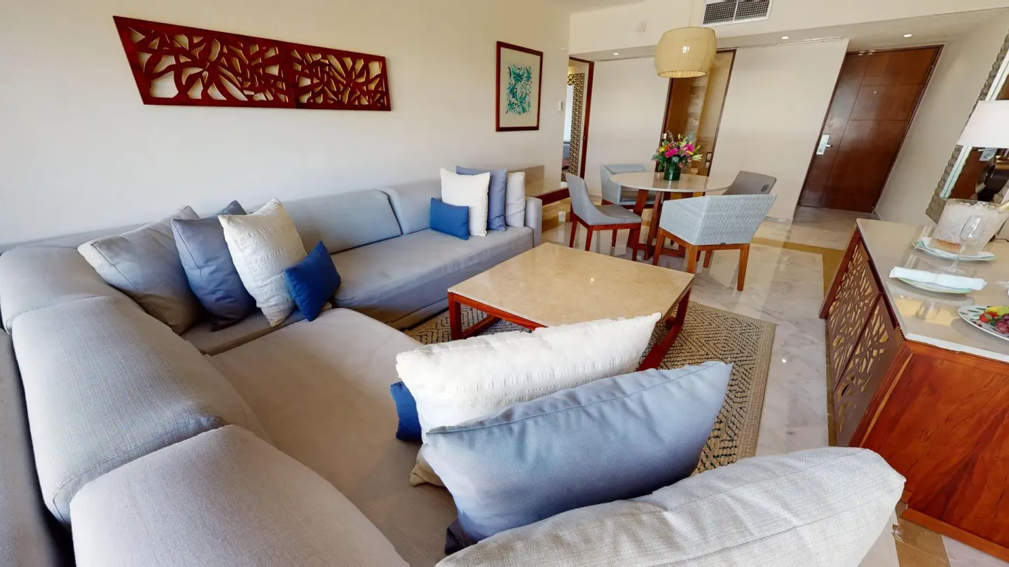 Family Suite living area with sectional sofa, coffee table, and dining table at Park Royal Beach Cancun.