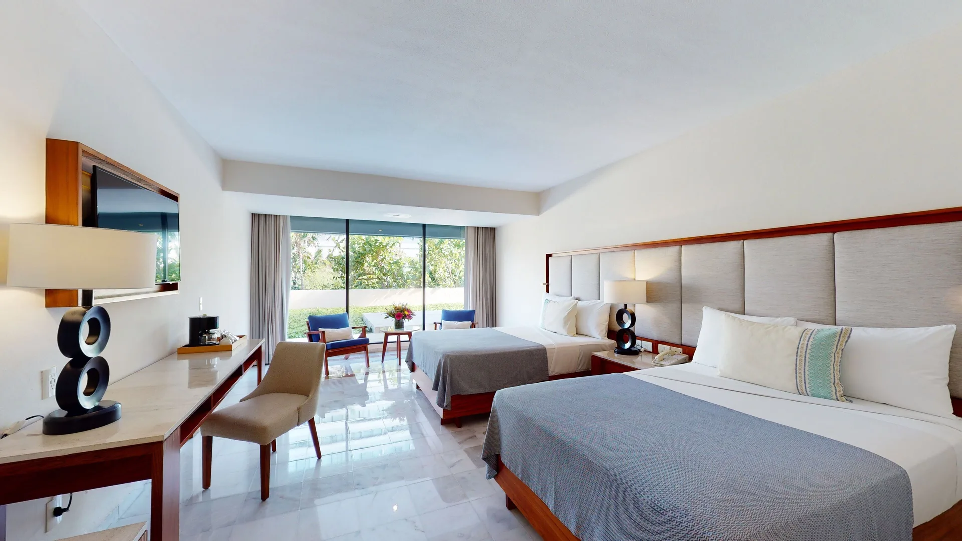 Family Suite bedroom with two beds and seating by the window at Park Royal Beach Cancun.