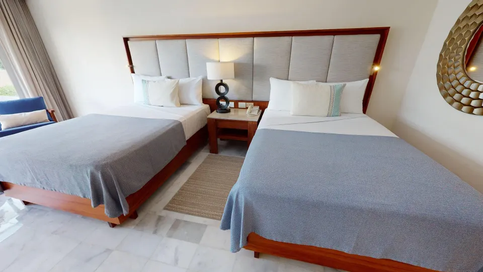 Two beds with gray covers and a shared nightstand in a Family Suite at Park Royal Beach Cancun.