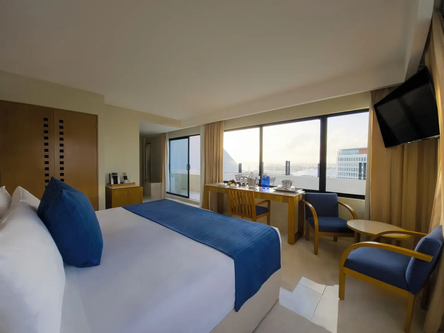 Honeymoon Room king bed with desk and seating area at Park Royal Beach Cancun.