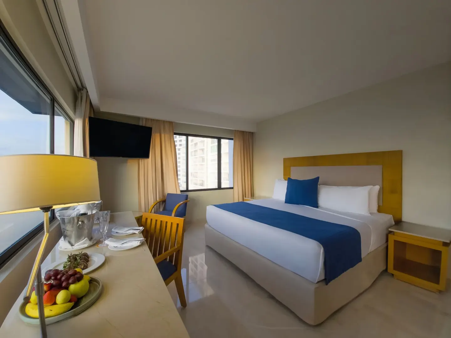 Honeymoon Room king bed and welcome fruit by the window at Park Royal Beach Cancun.