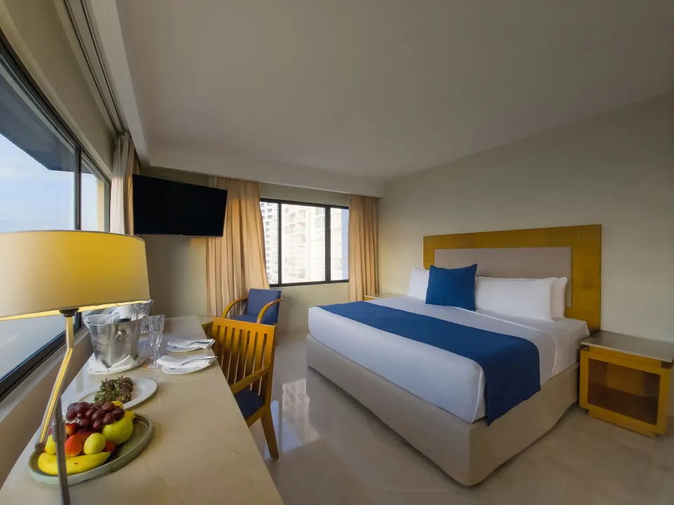Honeymoon Room king bed and welcome fruit by the window at Park Royal Beach Cancun.