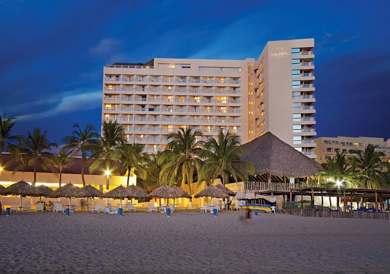 Illuminated beachfront hotel tower at dusk at Park Royal Beach Ixtapa.