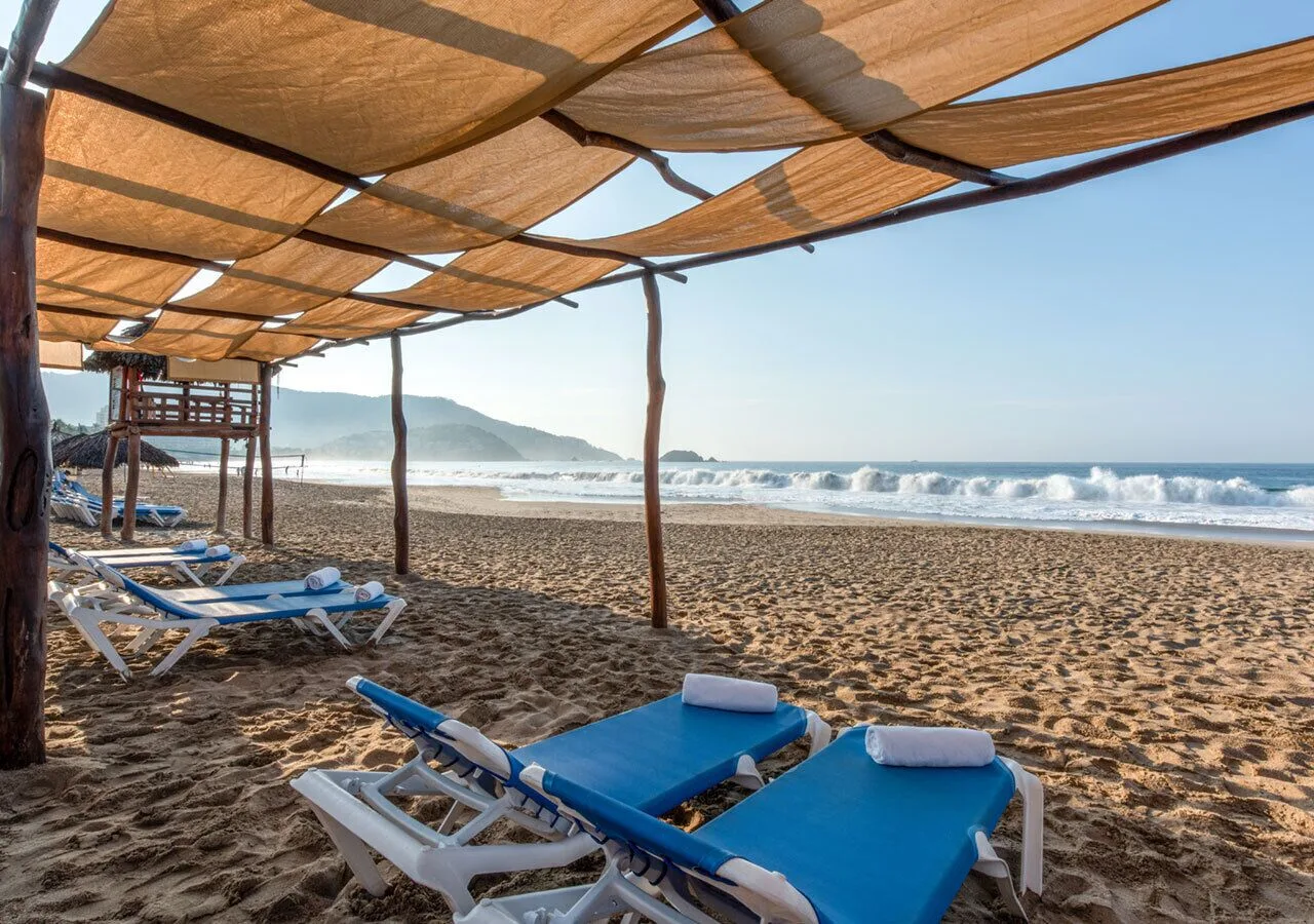 Blue beach loungers under shade canopies at Park Royal Beach Ixtapa.