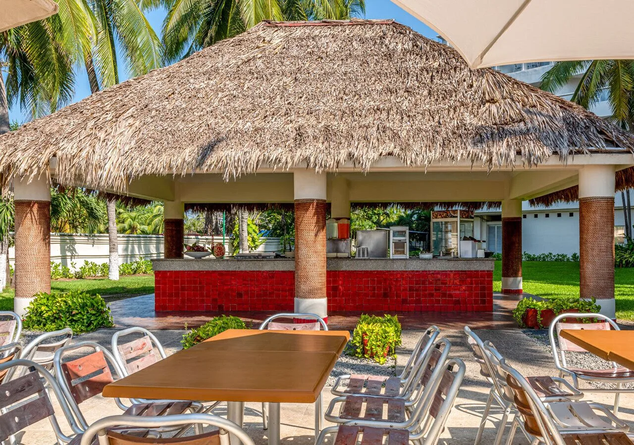 Thatched outdoor bar with patio tables at Park Royal Beach Ixtapa.
