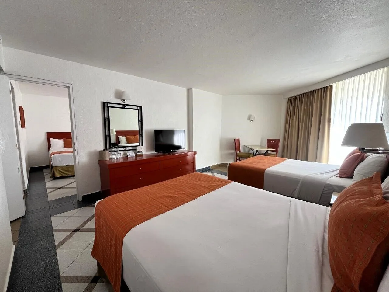 Family Suite with two beds, seating area, and adjoining room at Park Royal Beach Ixtapa.