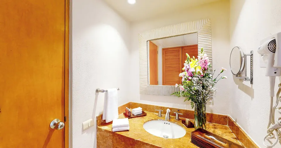 Master Suite bathroom vanity at Park Royal Beach Ixtapa with marble-look counter, flowers, towels, and mirror.