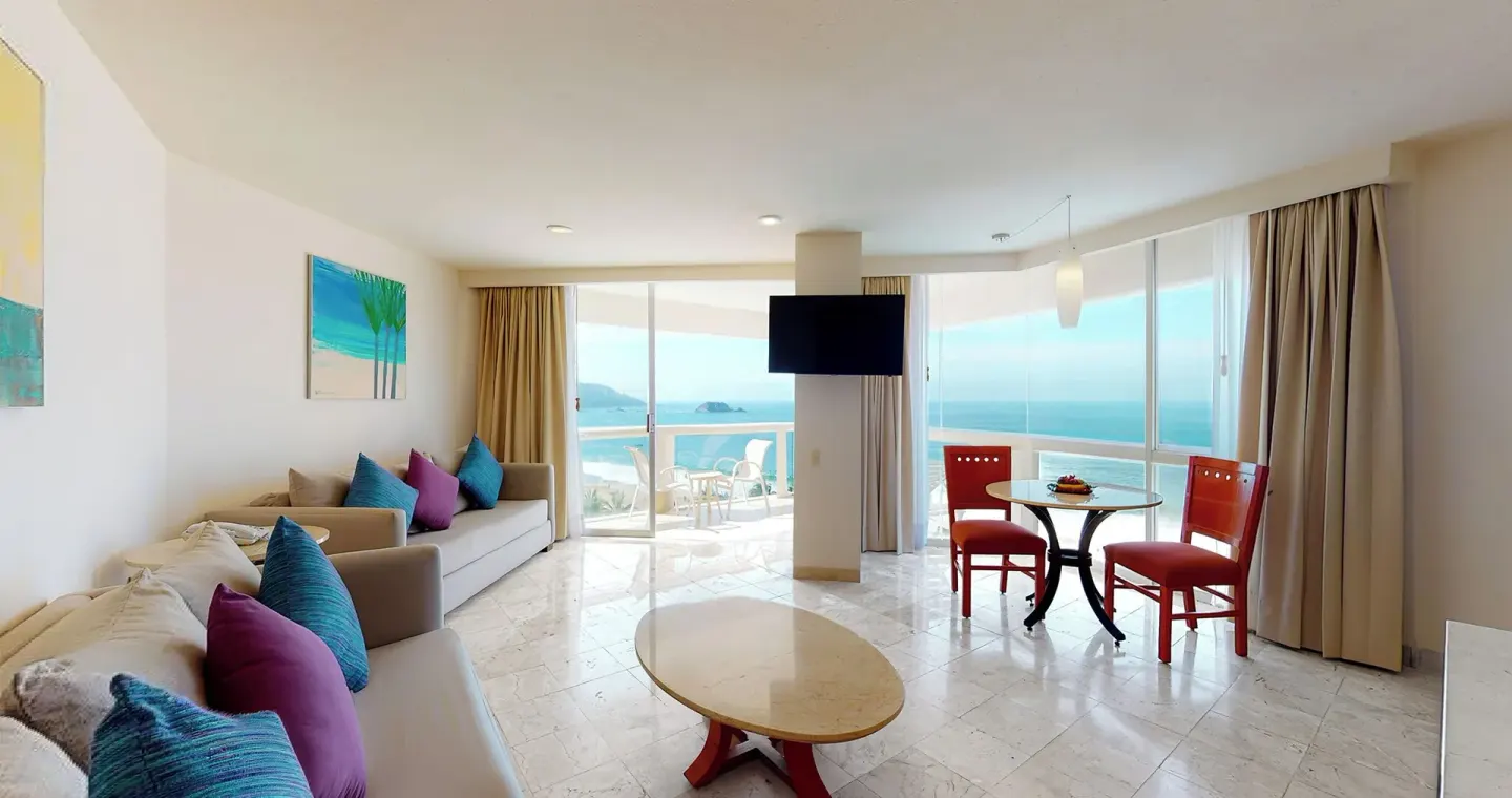Master Suite living room with sofas, dining table, TV, and ocean view at Park Royal Beach Ixtapa.