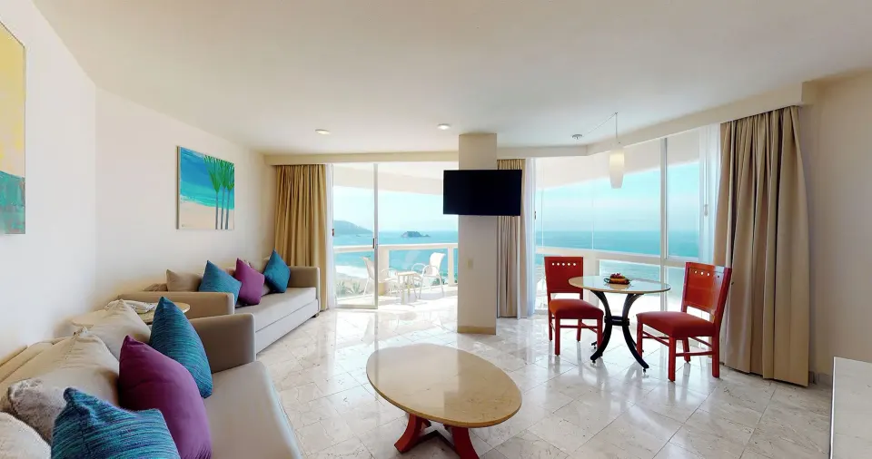 Master Suite living room with sofas, dining table, TV, and ocean view at Park Royal Beach Ixtapa.