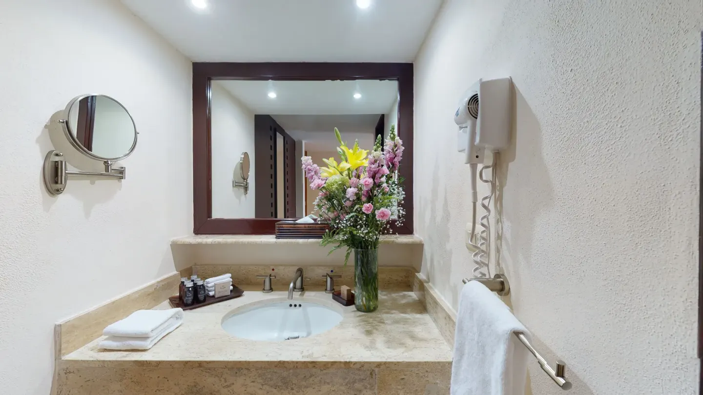 Royal Ocean Front bathroom vanity with flowers and mirror at Park Royal Beach Ixtapa.