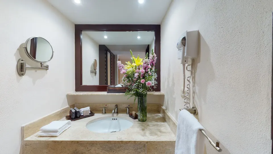 Royal Ocean Front bathroom vanity with flowers and mirror at Park Royal Beach Ixtapa.