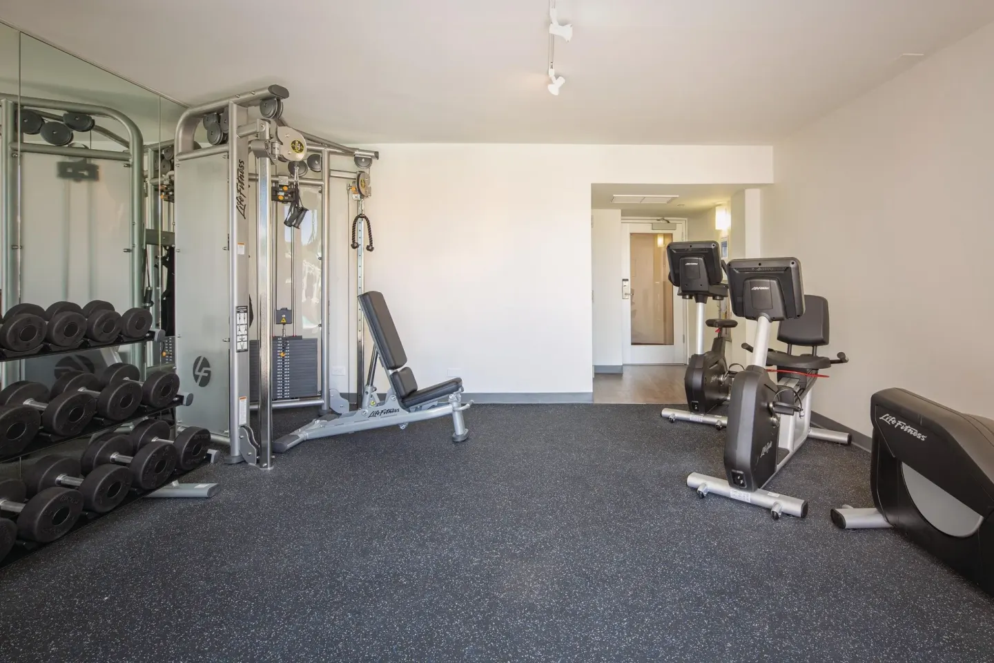 Fitness room with cable station, dumbbells, bikes, and open floor space at Park Shore Waikiki.