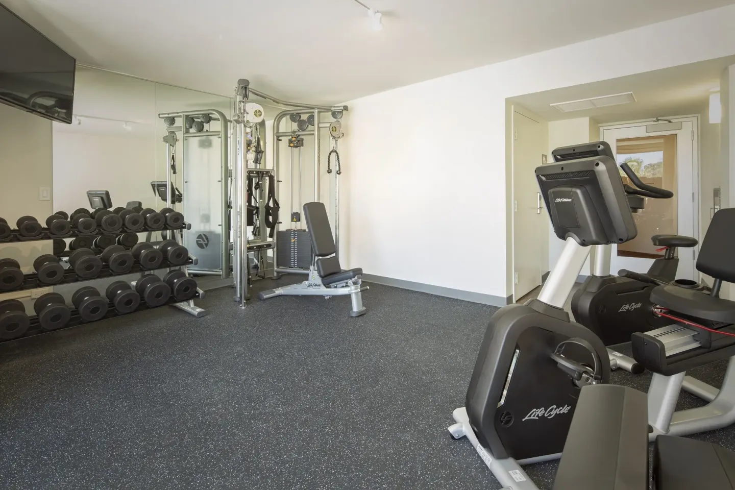 Fitness room with dumbbells, cable machine, and cardio equipment at Park Shore Waikiki.